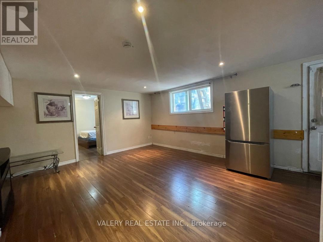 A spacious room with wooden flooring and a large window.