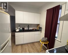 A kitchen with white cabinets and a black countertop.