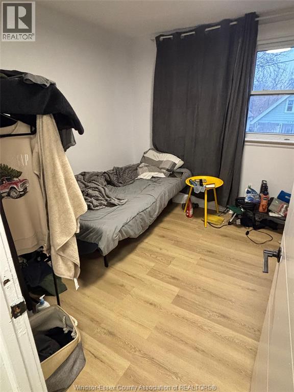A bedroom with a bed, a chair, and a window with black curtains.