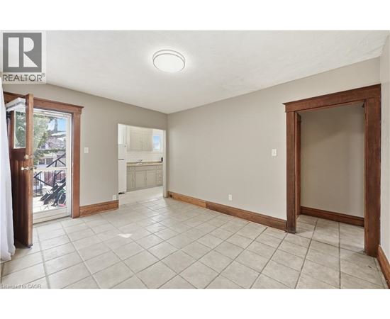 A spacious room with tiled flooring and a sliding glass door leading to a balcony.