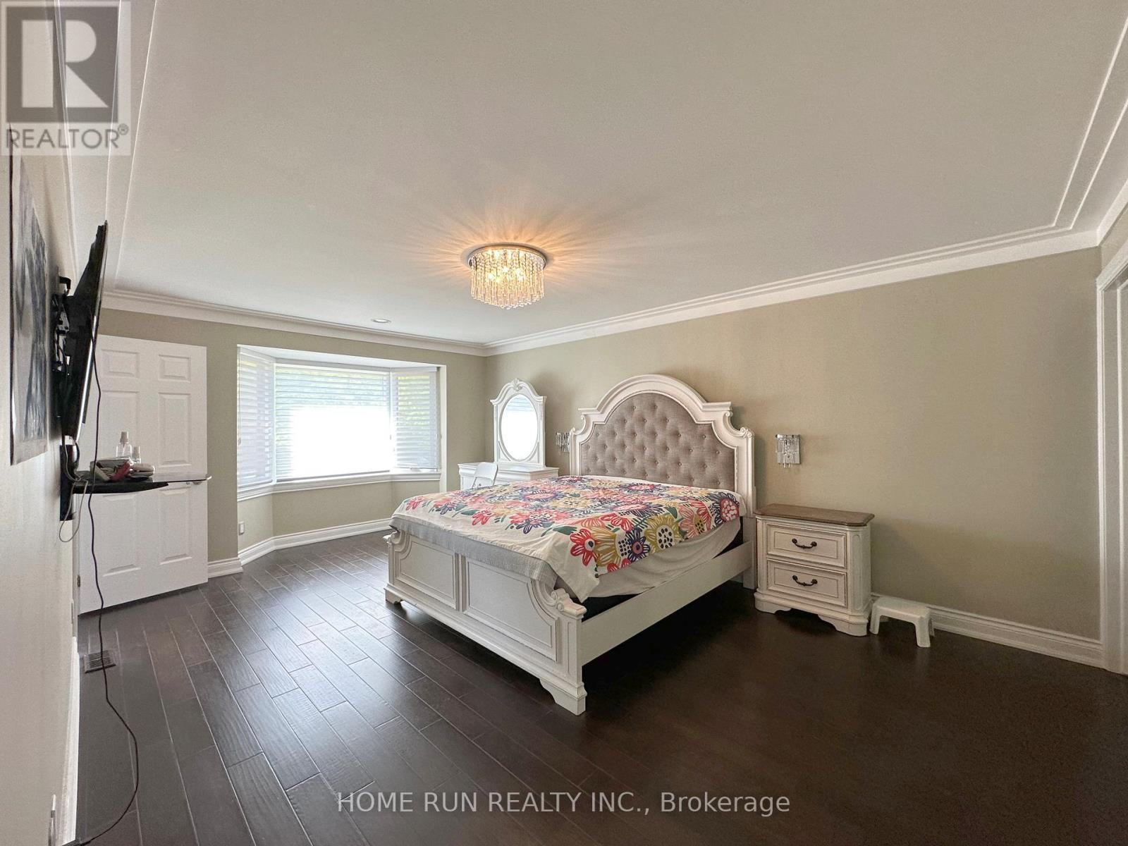 A bedroom with a large bed and a television on the wall.