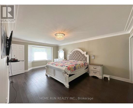 A bedroom with a large bed and a television on the wall.