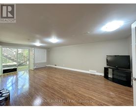 A spacious room with wooden flooring and a television on a stand.