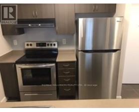 A stainless steel refrigerator stands next to a stove in a kitchen.