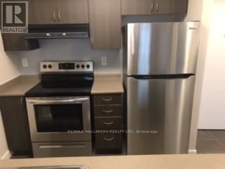 A stainless steel refrigerator stands next to a stove in a kitchen.