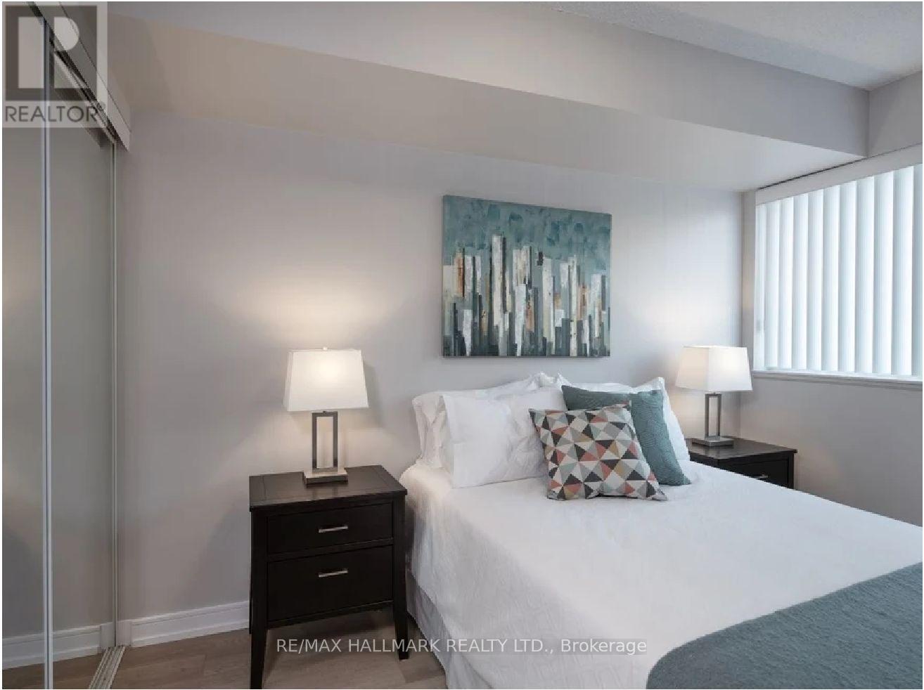 A bedroom with a bed, two lamps, and a painting on the wall.