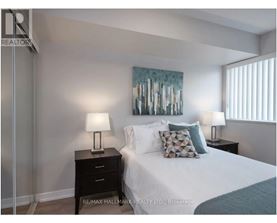 A bedroom with a bed, two lamps, and a painting on the wall.