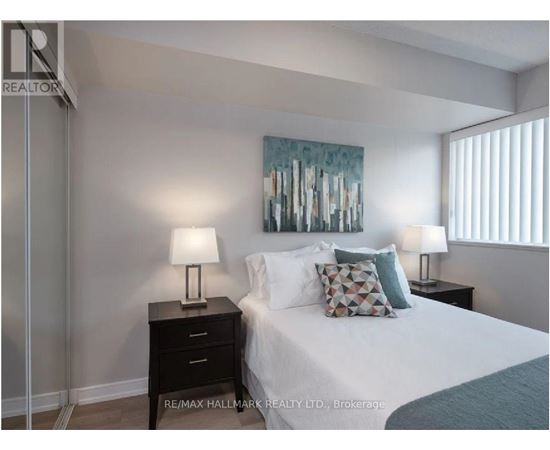 A bedroom with a bed, two lamps, and a painting on the wall.