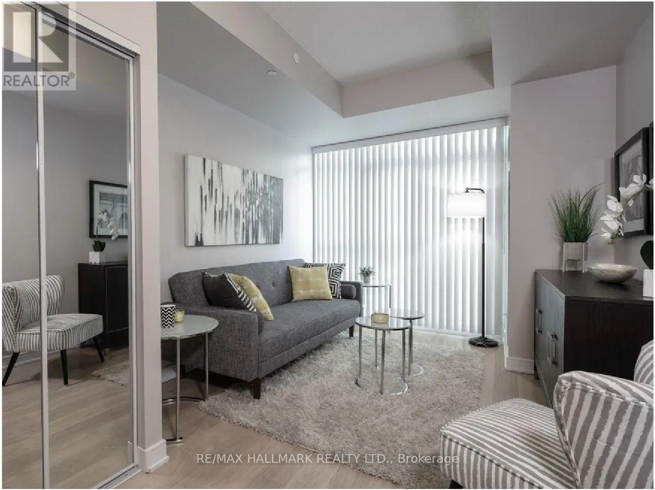 A living room with a grey couch and a painting on the wall.