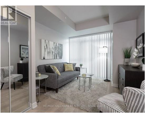 A living room with a grey couch and a painting on the wall.