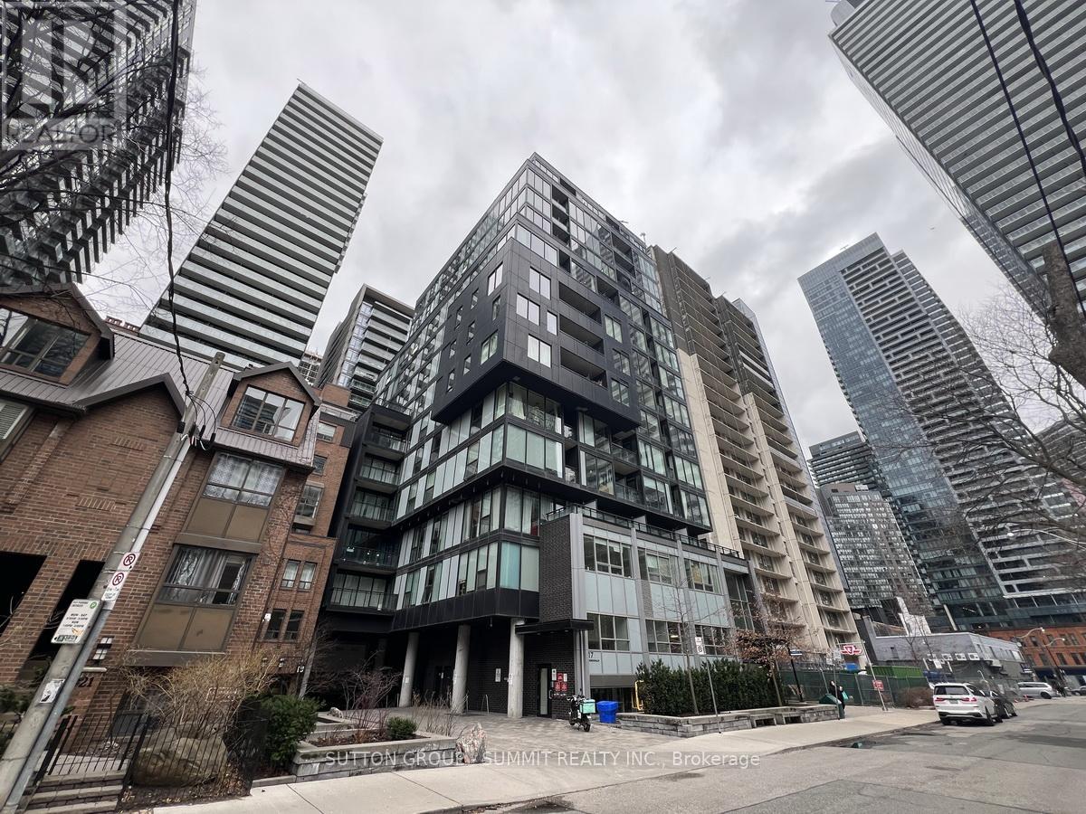 A tall building with many windows is in the foreground of a city street.