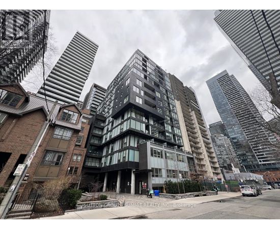 A tall building with many windows is in the foreground of a city street.