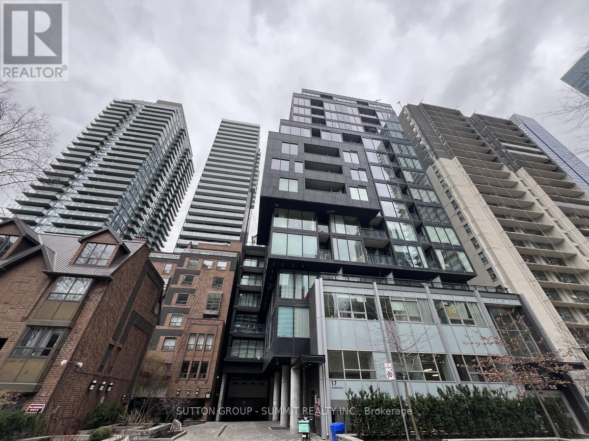A tall building with a glass facade stands in front of other buildings.
