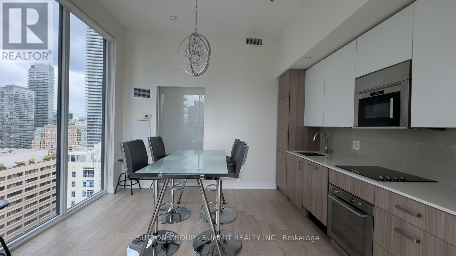 A modern kitchen with a dining table and chairs in front of a large window.