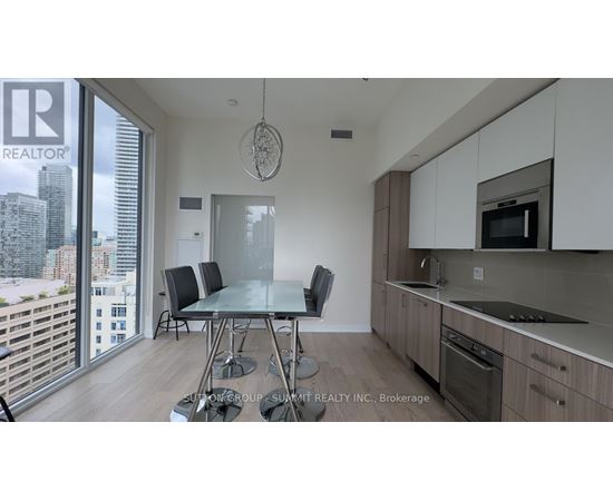 A modern kitchen with a dining table and chairs in front of a large window.