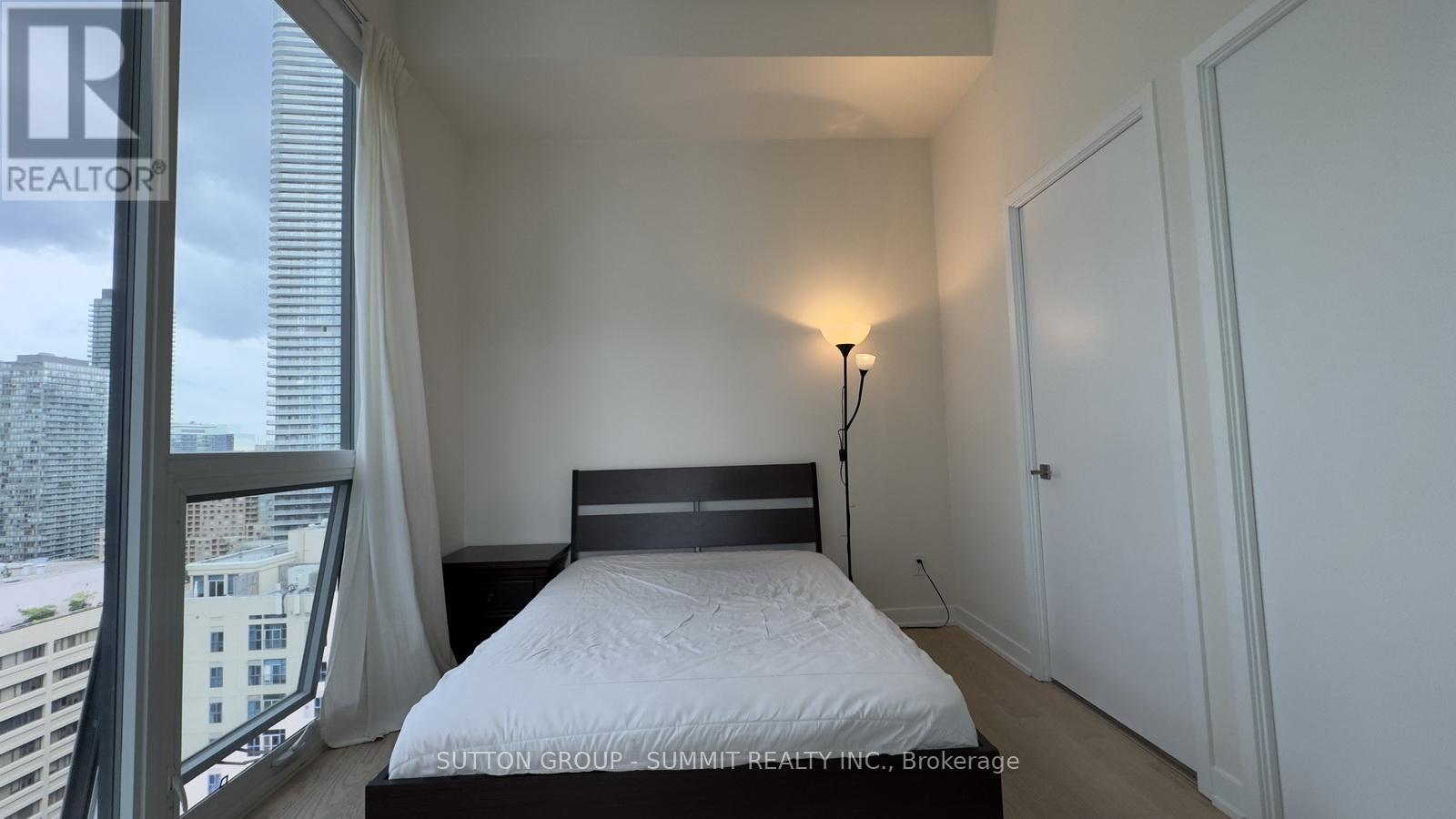 A bedroom with a large bed and a window overlooking a cityscape.
