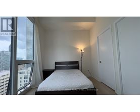 A bedroom with a large bed and a window overlooking a cityscape.