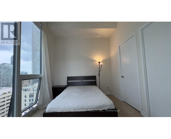 A bedroom with a large bed and a window overlooking a cityscape.