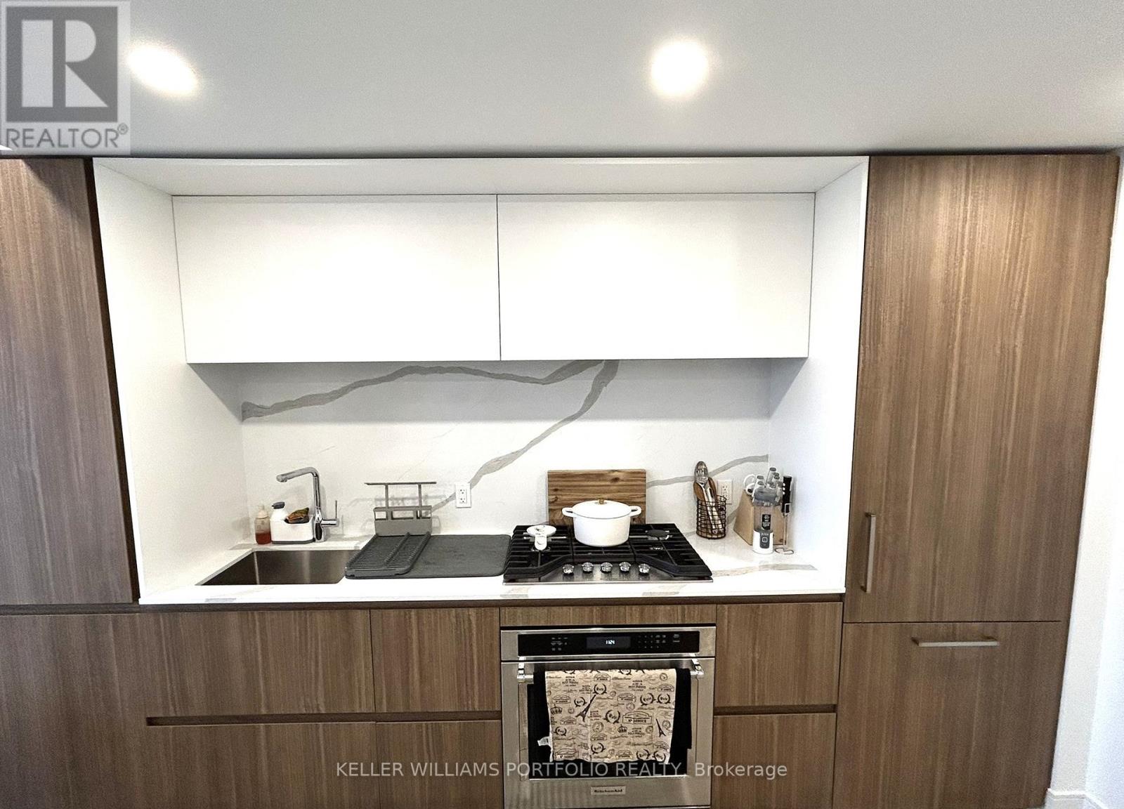 A modern kitchen with a stove top oven and wooden cabinets.
