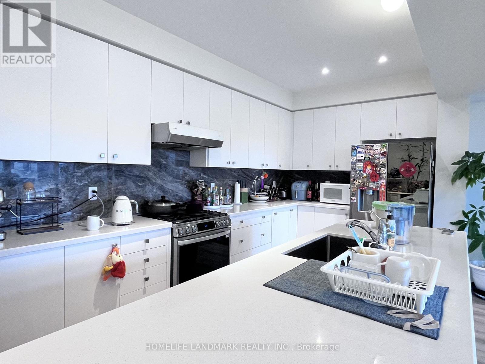 A modern kitchen with white cabinets and a marble backsplash.