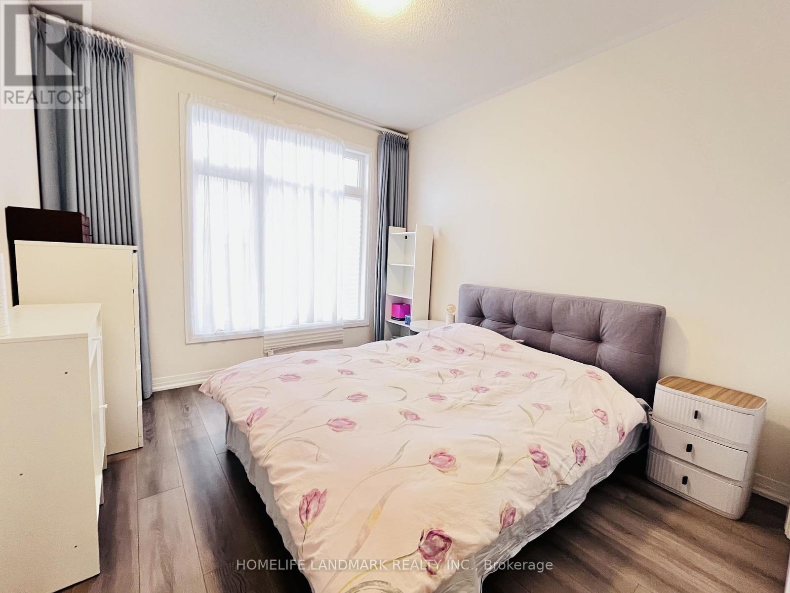 A bedroom with a bed, nightstand, and window.
