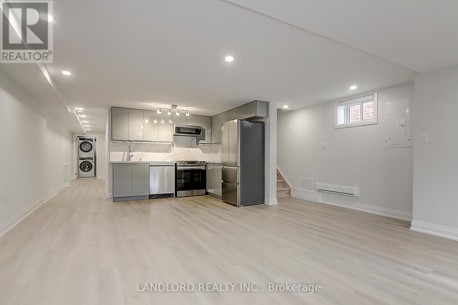 A spacious kitchen with white cabinets and a wooden floor.