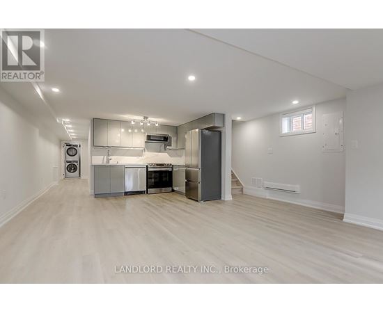 A spacious kitchen with white cabinets and a wooden floor.