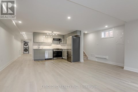 A spacious kitchen with white cabinets and a wooden floor.