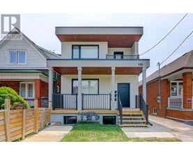A two-story house with a balcony and a black door is for sale.