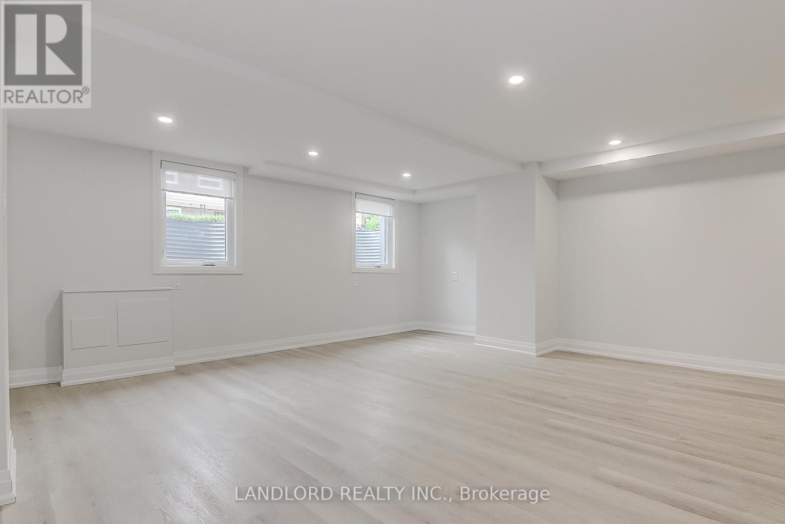 A spacious room with wooden flooring and white walls.