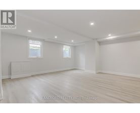 A spacious room with wooden flooring and white walls.