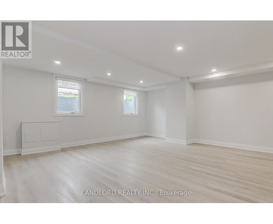 A spacious room with wooden flooring and white walls.