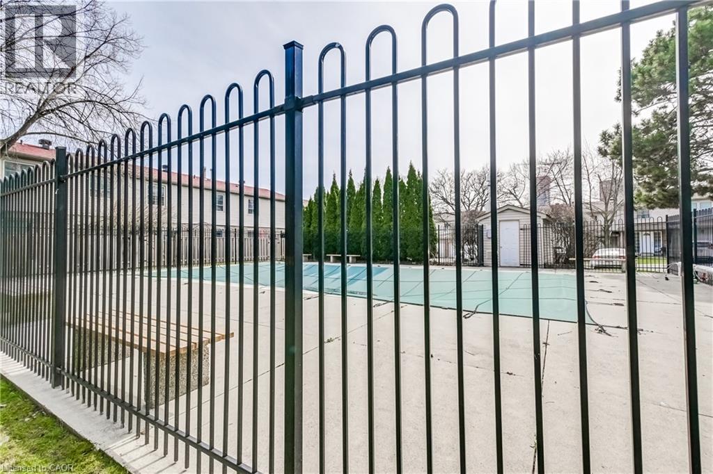 A black metal fence surrounds a green pool.
