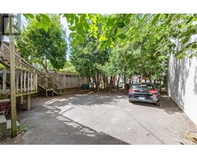 A car is parked in a driveway surrounded by trees.