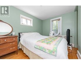 A bedroom with a bed, dresser, and window.