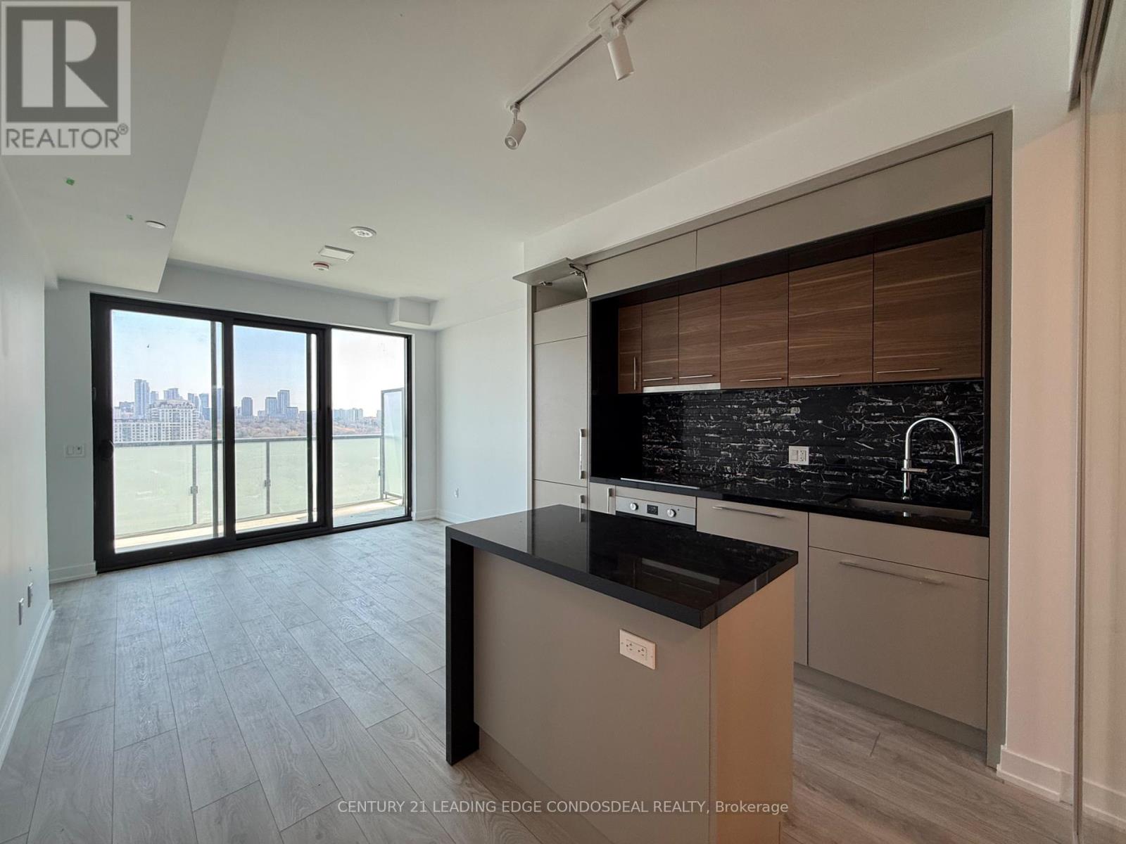 A kitchen with a black countertop and a view of the city through the windows.