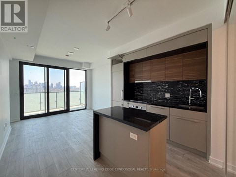 A kitchen with a black countertop and a view of the city through the windows.