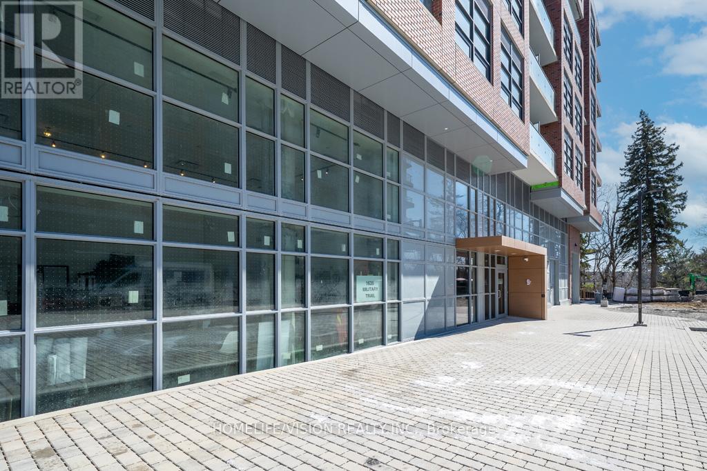 A modern building with glass windows and a brick walkway in front.
