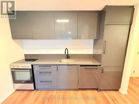 A kitchen with a stainless steel refrigerator, oven, and sink.