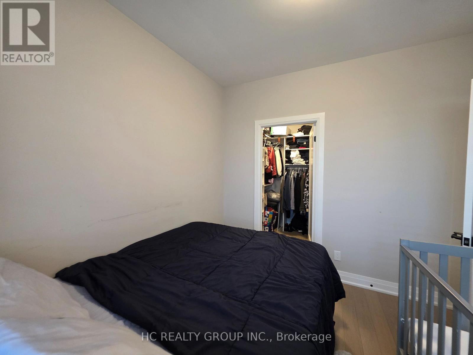 A bedroom with a bed and a closet with clothes.