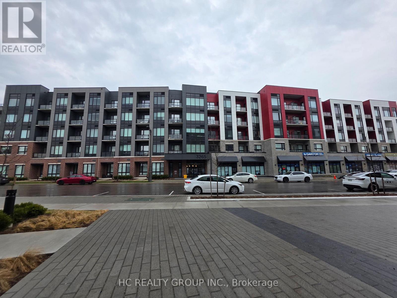 A row of modern apartment buildings with cars parked in front.