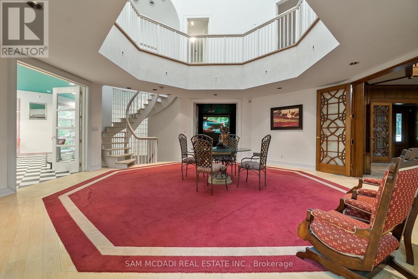 A living room with a red carpet and a spiral staircase.