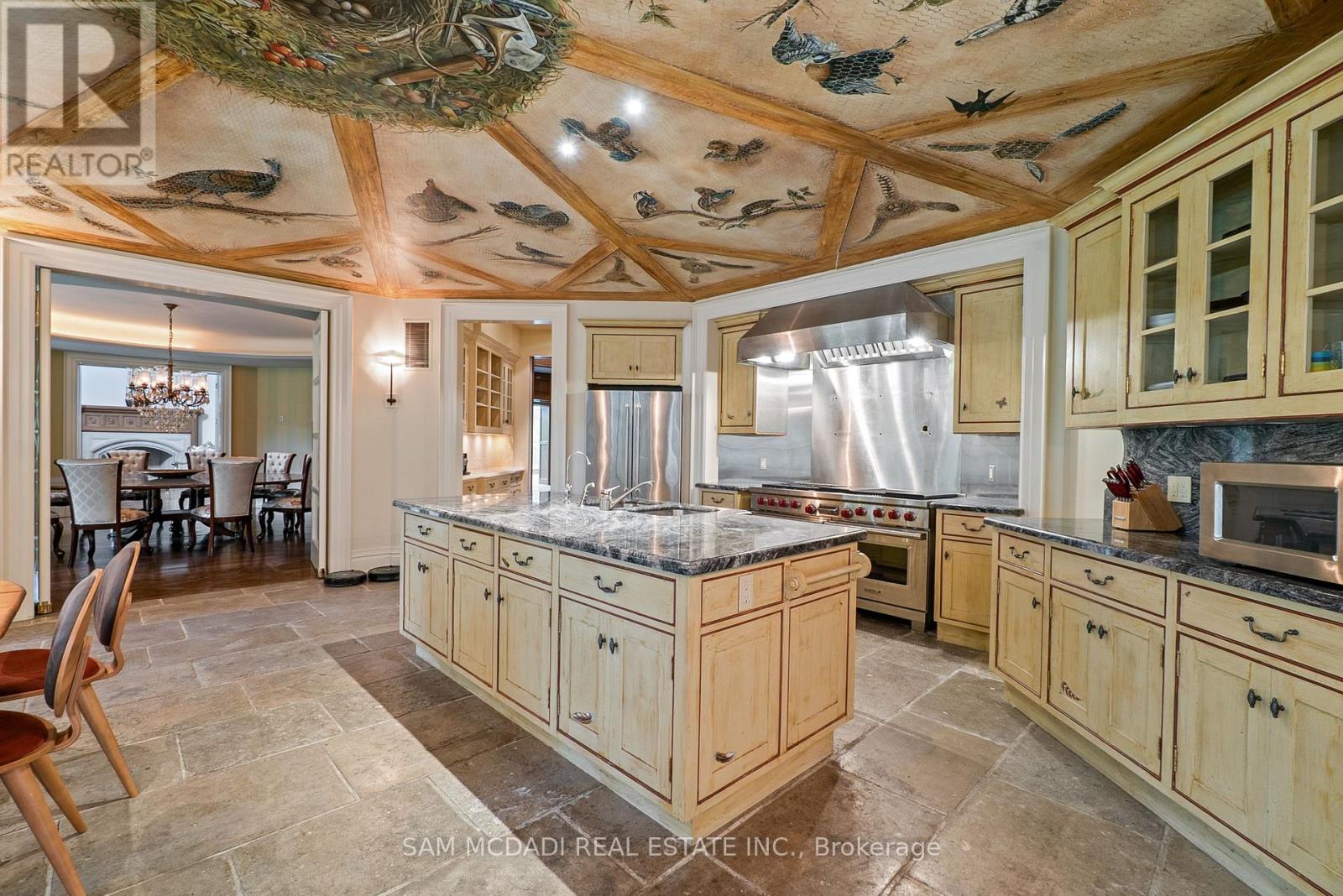 A kitchen with wooden cabinets and a ceiling mural of flying birds.