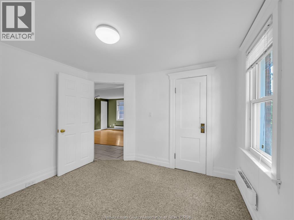 A white bedroom with a carpet floor and a window.