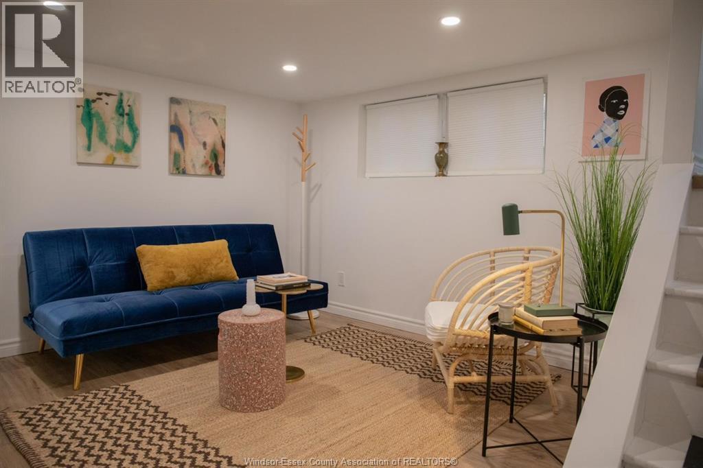 A blue sofa with a yellow pillow sits in a room with a wicker chair and a small table.
