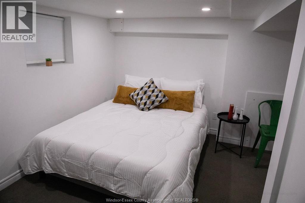 A bedroom with a white bed and a green chair.