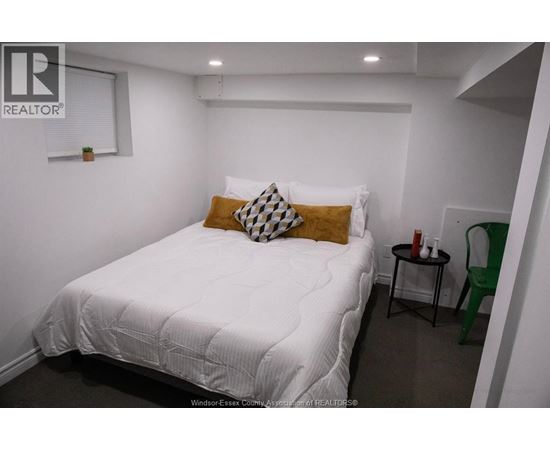 A bedroom with a white bed and a green chair.