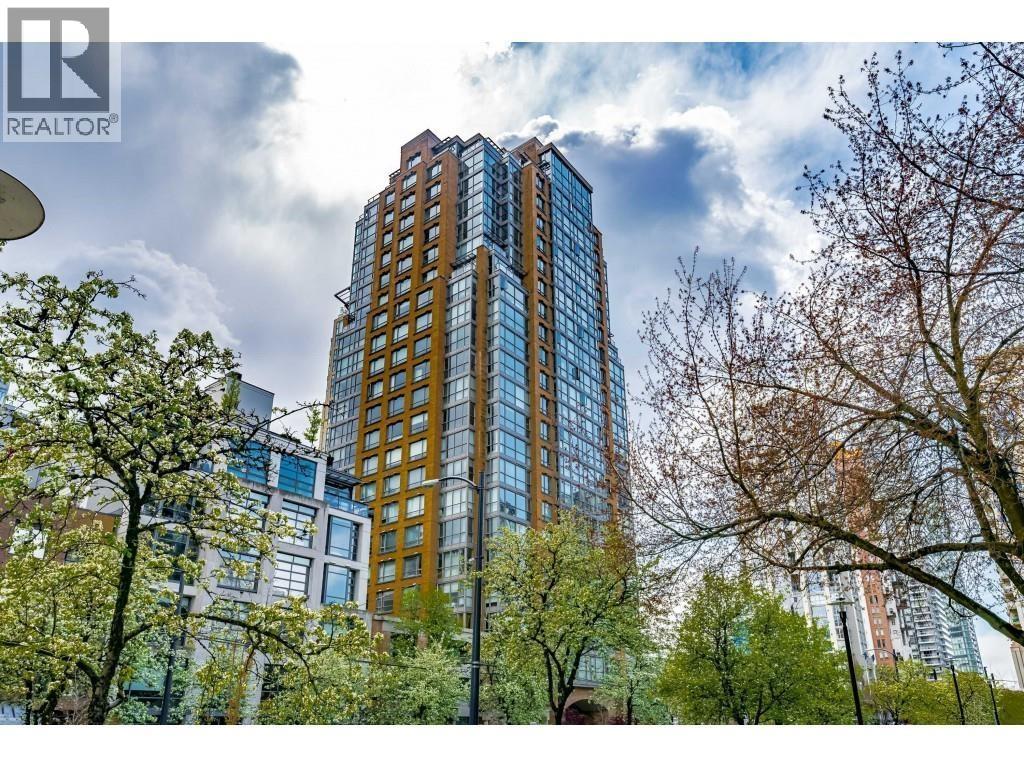 A tall building with many windows is surrounded by trees.