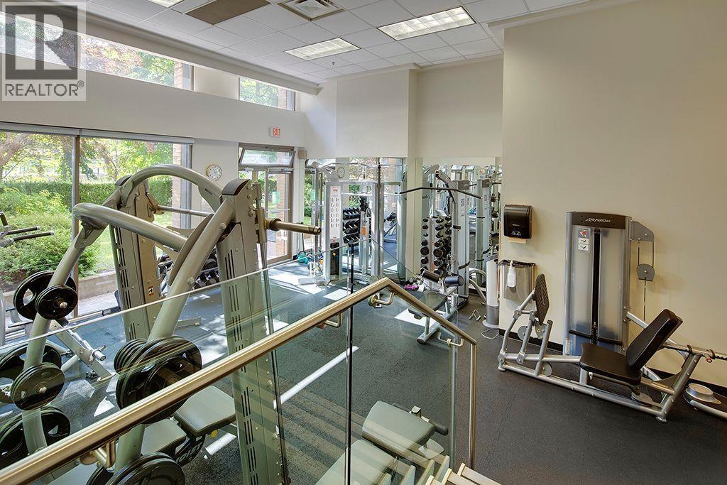 A gym with a glass railing and weights.
