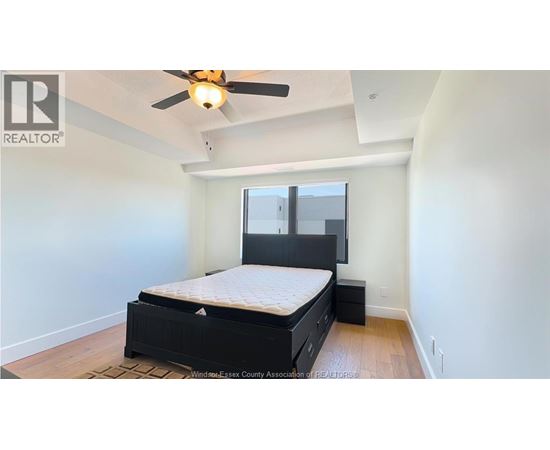 A bedroom with a bed, dresser, and ceiling fan.